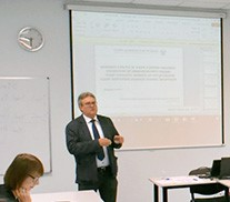 Na zdjęciu jest ukazany mężczyzna, Andrzej Bugalski Stoi on przed tablicą multimedialną.